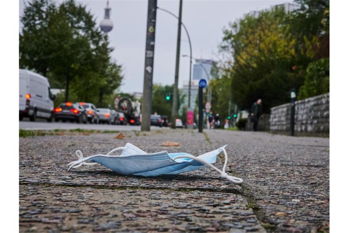 Ein Mund-Nasen-Schutz liegt auf dem Gehweg in Berlin-Friedrichshain. Foto: Annette Riedl/dpa