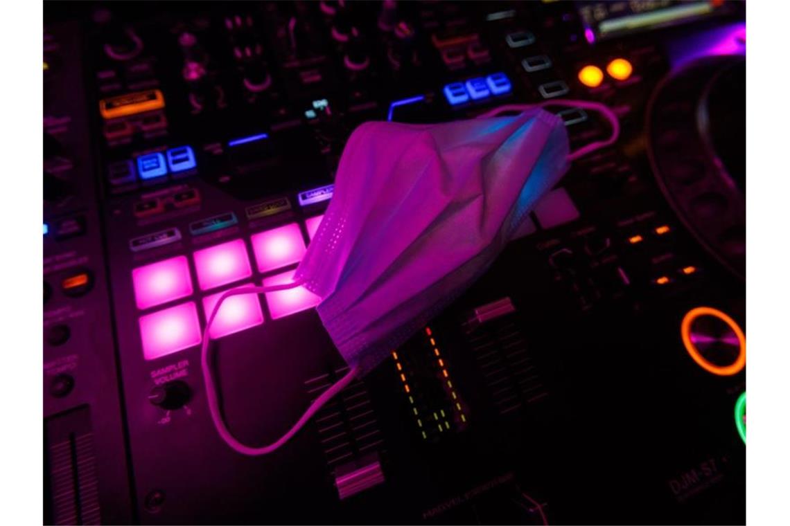 Ein Mund-Nasen-Schutz liegt auf dem Mischpult des DJs in einem Club. Foto: Philipp von Ditfurth/dpa/Illustration