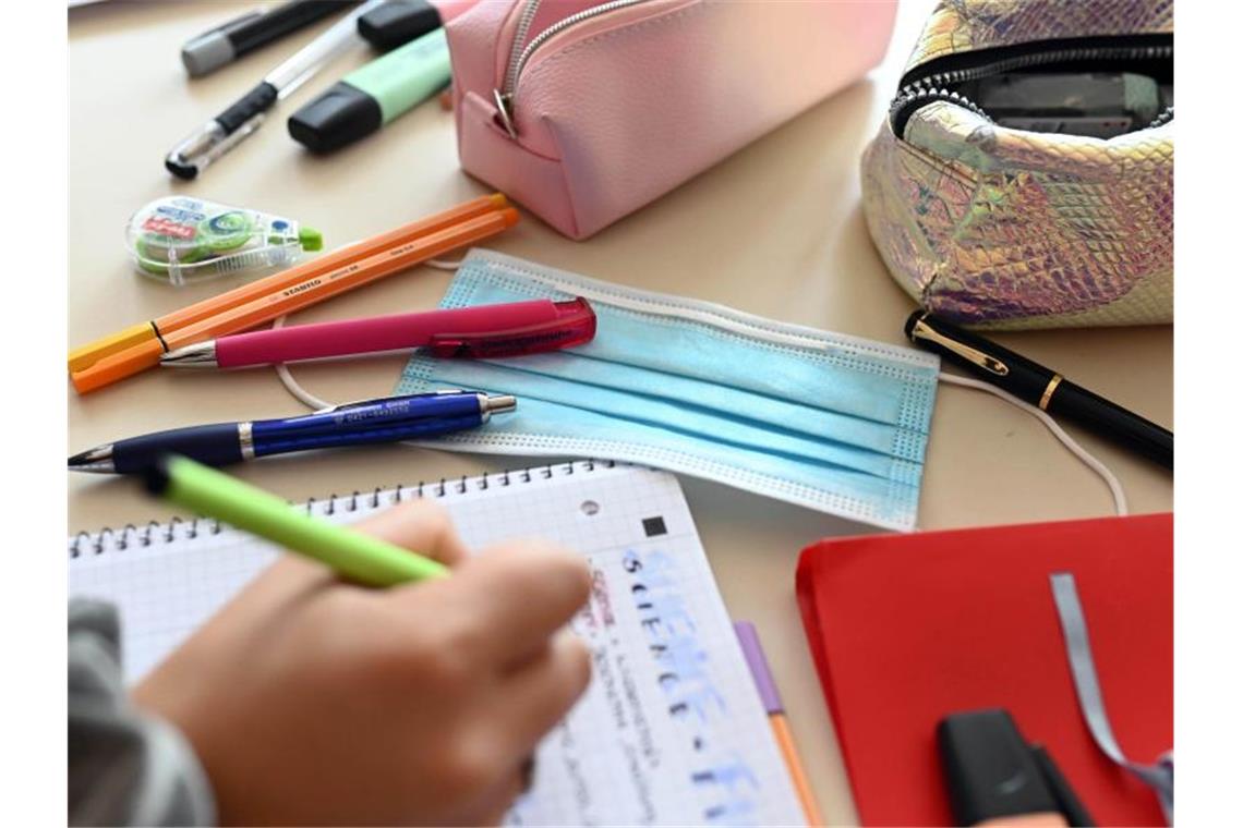 Gewerkschaft: Kita- und Schulöffnung ist „utopisch“ Ein Mund-Nasen-Schutz liegt auf dem Tisch einer Schülerin. Foto: Uli Deck/dpa/Symbolbild
