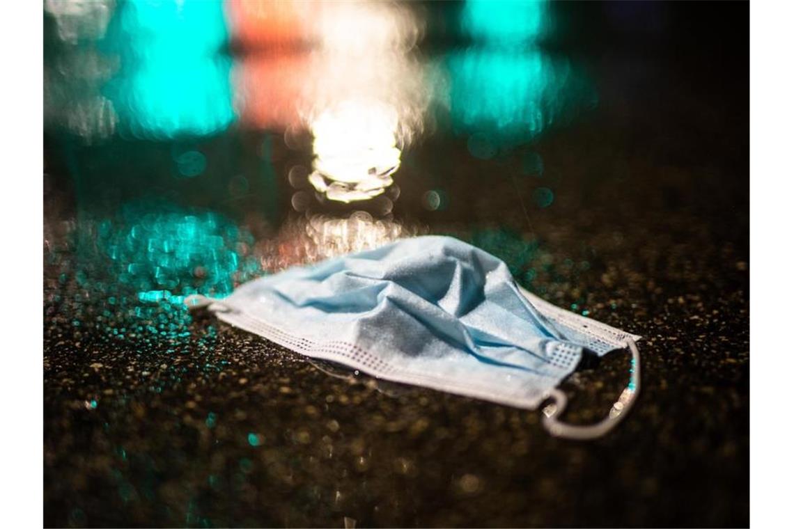 Corona-Inzidenz im Südwesten sinkt Ein Mund-Nasenschutz liegt im Regen auf der Strasse. Foto: Christoph Schmidt/dpa/Symbolbild