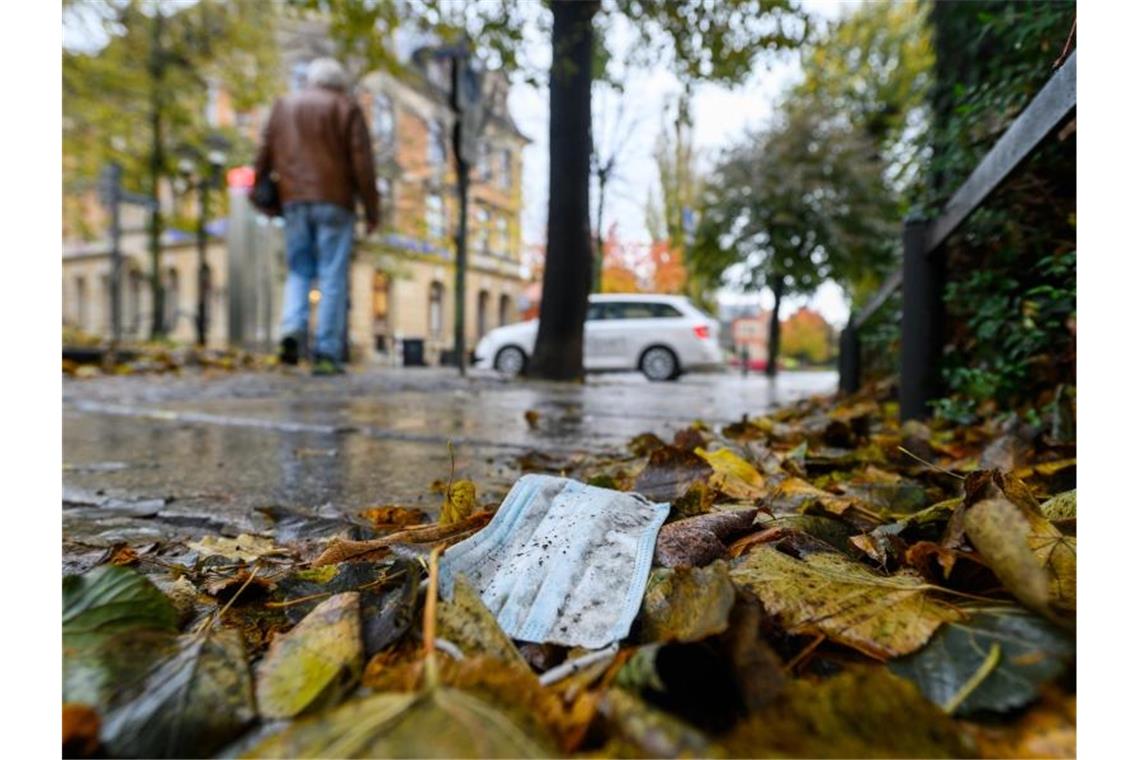 RKI registriert 20.398 Corona-Neuinfektionen Ein Mundschutz zwischen herbstlich gefärbten Blättern in der Altstadt von Pirna. Foto: Robert Michael/dpa-Zentralbild/dpa