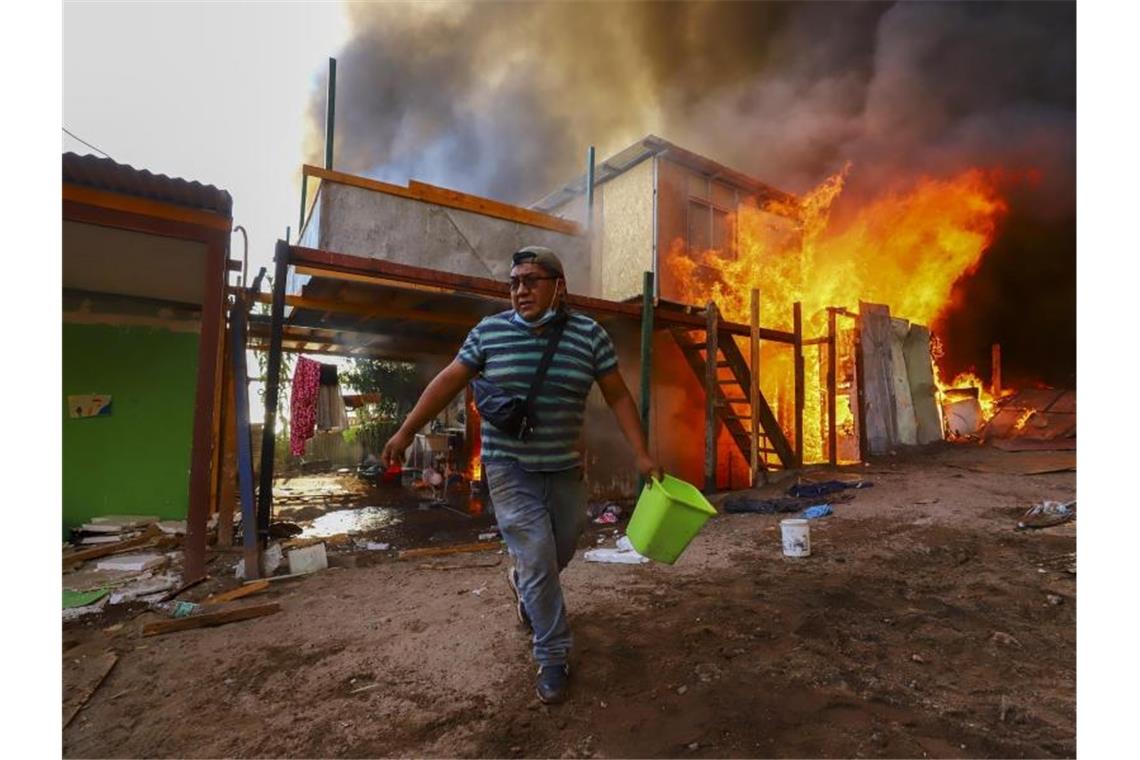 Rund 100 Häuser bei Großbrand im Norden von Chile zerstört Ein Nachbar hilft bei der Bekämpfung eines Brandes in dem einkommensschwachen Viertel Laguna Verde in Iquique, Chile. Foto: Ignacio Munoz/AP/dpa