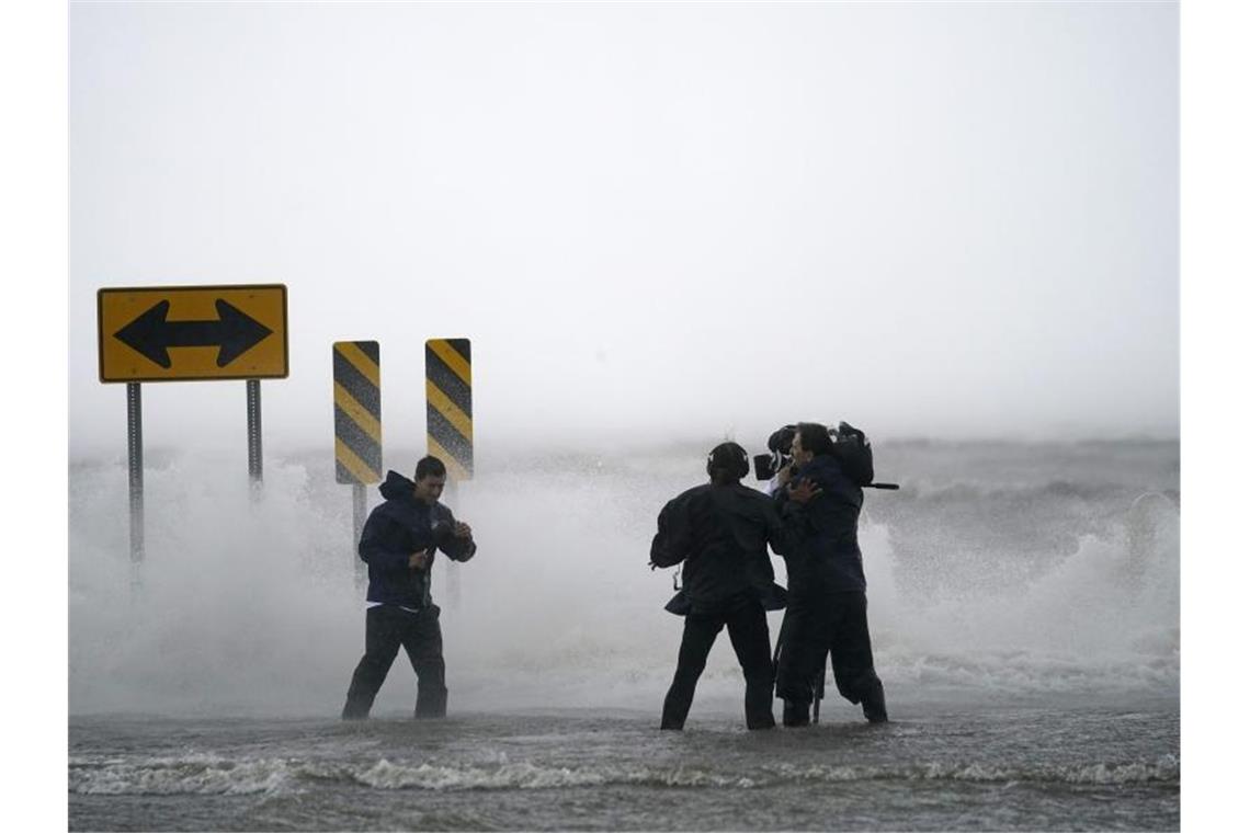 Ein Nachrichtenteam steht im Wasser des Lake Pontchartrains nördlich von New Orleans. Hurrikan „Ida“ könnte schwere Schäden anrichten. Foto: Gerald Herbert/AP/dpa