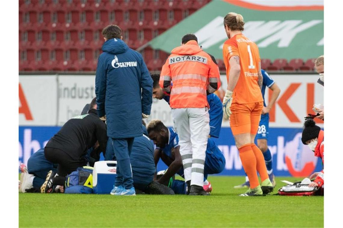 Ein Notarzt kümmert sich um Mark Uth. Die Verletzung des Schalke-Stürmers hat die Partie in Augsburg überschattet. Foto: Stefan Puchner/dpa