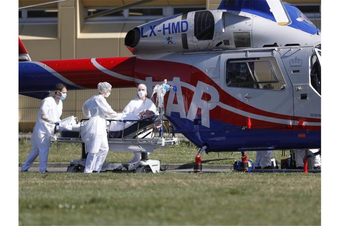 Ein Notfallpatient wird aus dem Zivilkrankenhaus von Mulhouse zu einem Hubschrauber gebracht. Vor allem im Département Haut-Rhin und in der gesamten ostfranzösischen Region Grand Est ist die Zahl der Corona-Infektionen dramatisch gestiegen. Foto: Jean-Francois Badias/AP/dpa