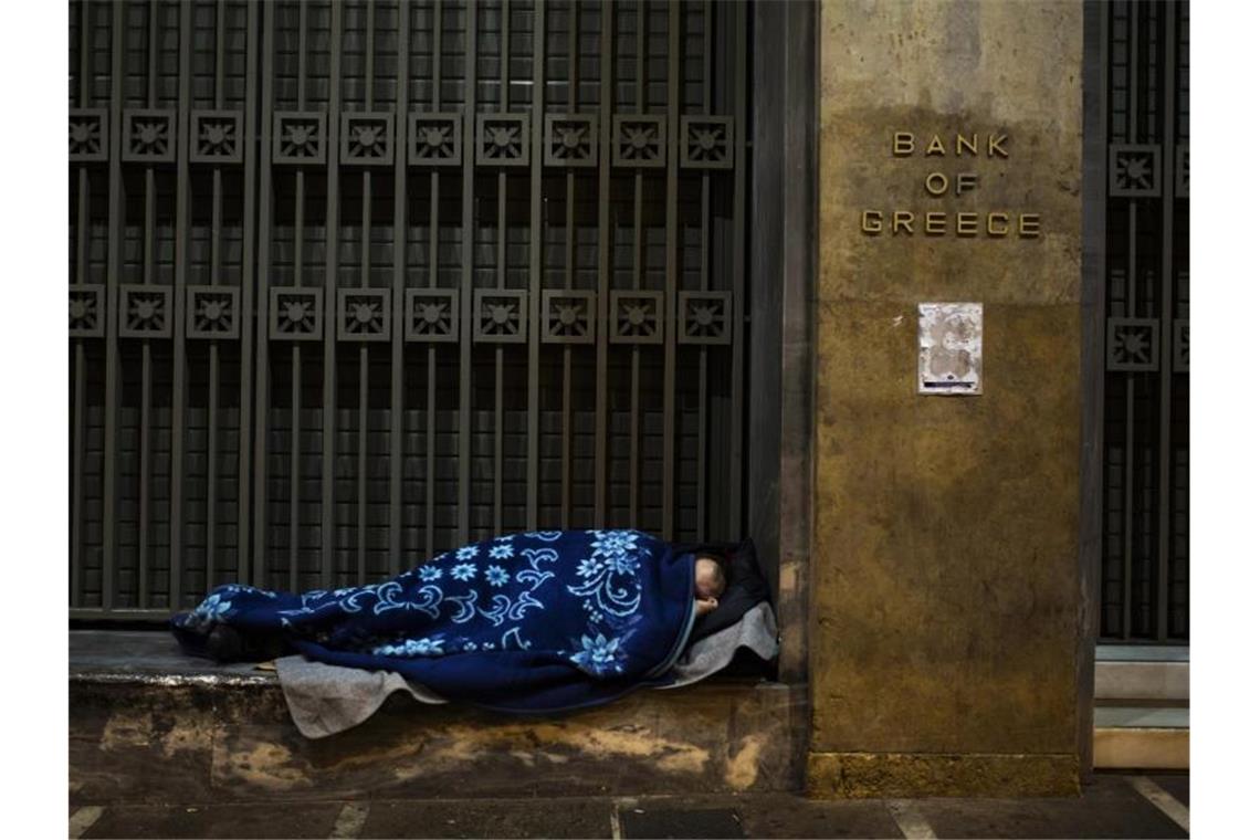 Ein Obdachloser hat sich vor der Bank von Griechenland in Athen zum Schlafen gelegt. Foto: Angelos Tzortzinis