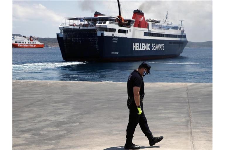 Ein Offizier der Küstenwache auf dem Dock vor einer Fähre zur Ägäisinsel Milos. Foto: Thanassis Stavrakis/AP/dpa