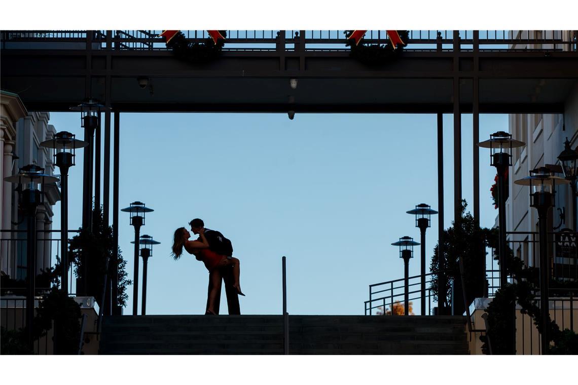 Ein Paar küsst sich an seinem einjährigen Hochzeitstag oben auf den Stufen der Jax Brewery im French Quarter von New Orleans.