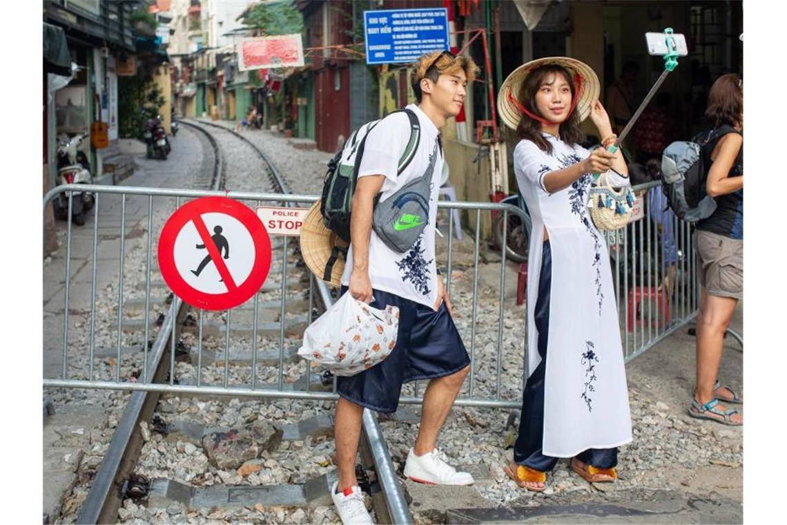 Ein Paar macht ein Selfie an der Absperrung zur „Train Street“: Touristen müssen sich in Hanoi von der berühmt gewordenen Sehenswürdigkeit verabschieden. Foto: Chris Humphrey/dpa