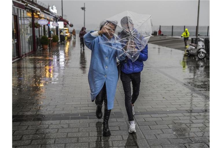 Ein Paar schützt sich mit einem Regenschirm vor starkem Wind und Regen in Istanbul. Foto: Uncredited/AP/dpa