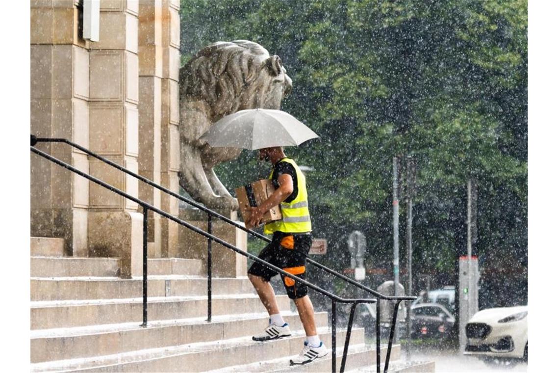 Hitze, Unwetter und Waldbrandgefahr Ein Paketbote bringt im Platzregen seine Lieferungen ins Neue Rathaus von Hannover. Foto: Julian Stratenschulte/dpa