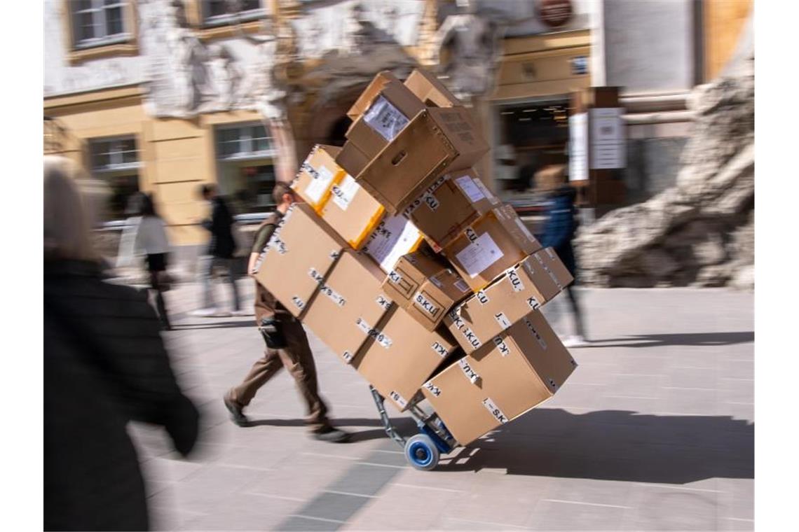 Ein Paketzulieferer transportiert mit einer Sackkarre mehrere Pakete durch die Fußgängerzone. Foto: Peter Kneffel/dpa