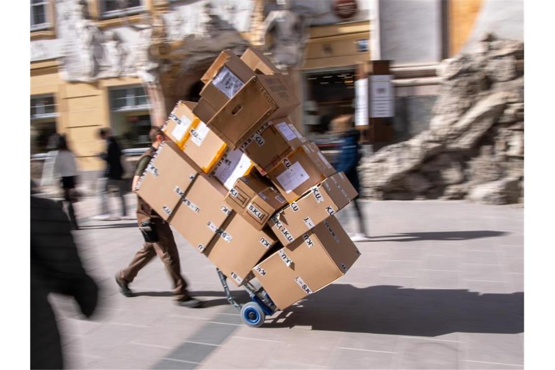 Ein Paketzulieferer transportiert mit einer Sackkarre mehrere Pakete durch die Münchener Innenstadt. Foto: Peter Kneffel/dpa