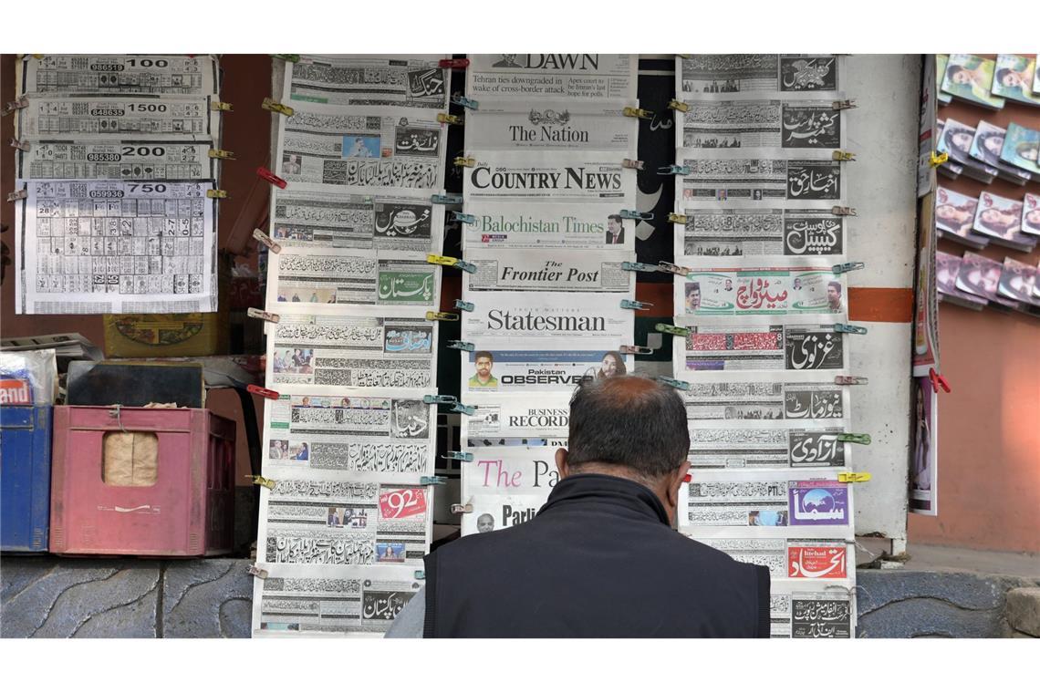 Ein Pakistaner liest an einem Verkaufsstand Tageszeitungen.