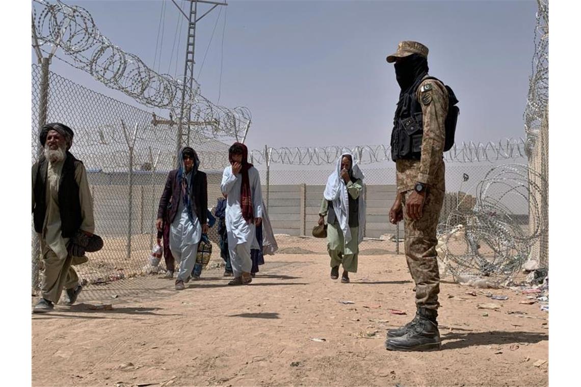 Ein pakistanischer Soldat steht Wache, während Menschen aus Afghanistan über einen Grenzübergang in Chaman nach Pakistan einreisen. Foto: Uncredited/AP/dpa