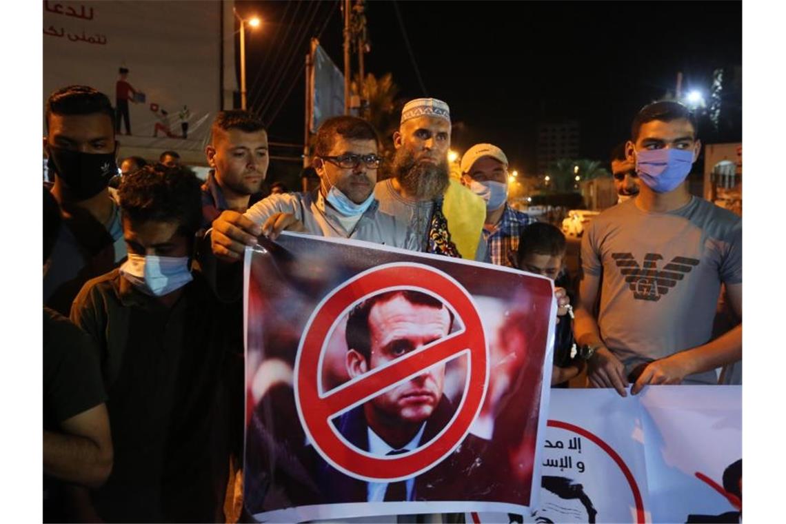 Ein Palästinenser hält bei einer Protestaktion in den palästinensischen Autonomiegebieten ein Anti-Macron-Plakat. Foto: Ashraf Amra/APA Images via ZUMA Wire/dpa