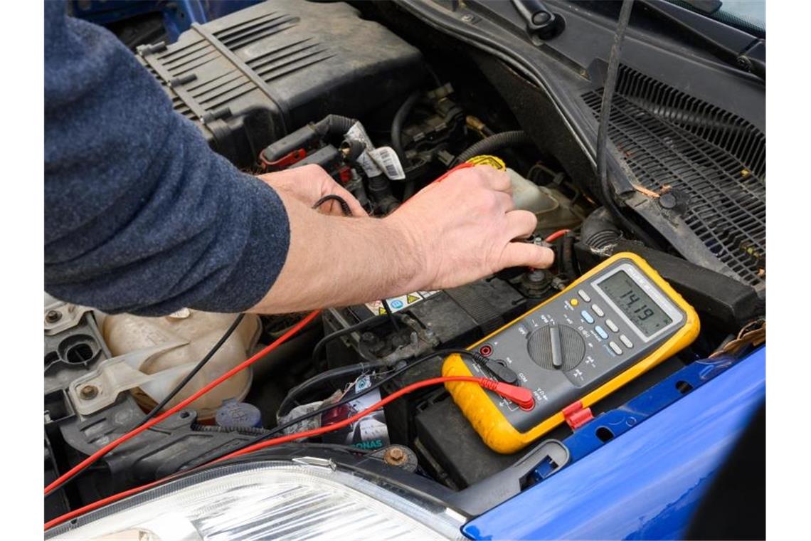 Zwei Schwerverletzte bei Arbeitsunfall in Autowerkstatt Ein Pannenhelfer misst an einem Auto die Spannung einer Autobatterie. Foto: Christophe Gateau/dpa/Symbolbild