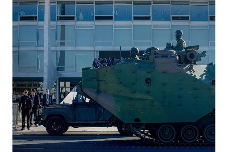 Ein Panzer fährt während einer Militärparade vor dem Regierungspalast, wo Präsident Jair Bolsonaro (M.) steht. Foto: Myke Sena/dpa