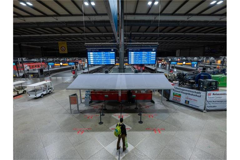 Ein Passagier steht am frühen Morgen am Münchner Hauptbahnhof am Infoschalter. Foto: Peter Kneffel/dpa