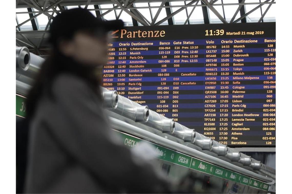 Ein Passagier steht vor einer Fluginformationstafel am Flughafen Rom-Fiumicino. Foto: Alessandra Tarantino/AP