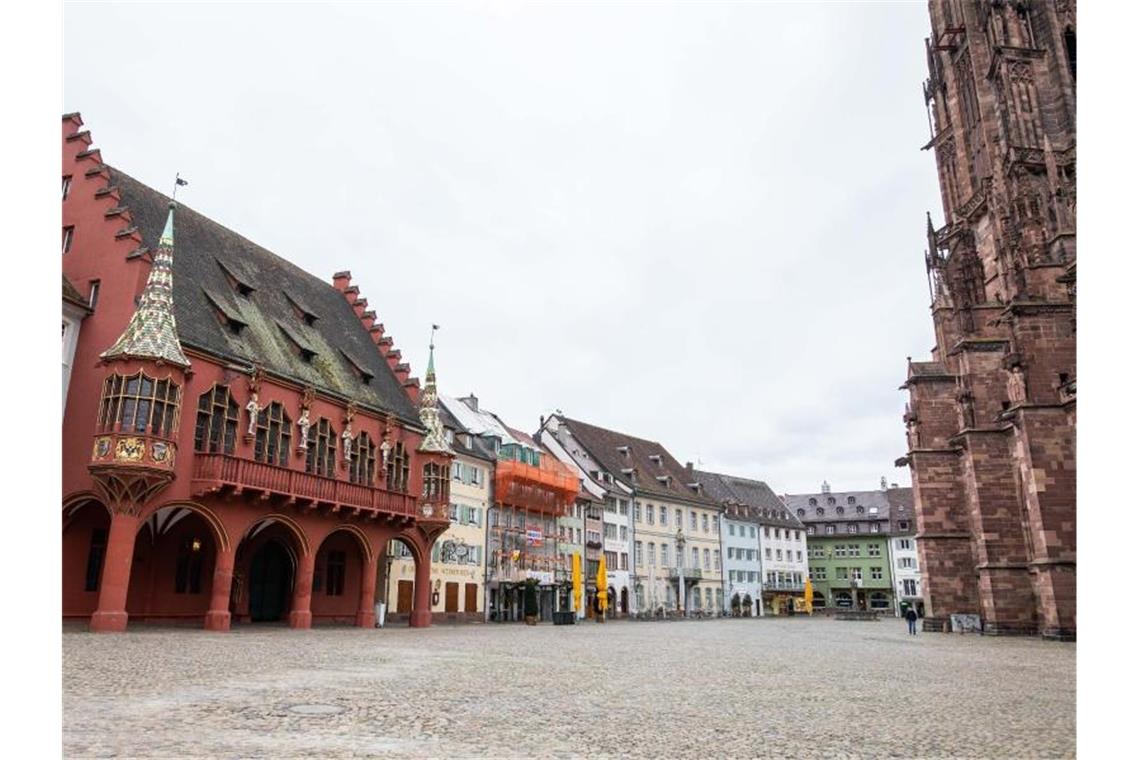 Ein Passant geht am späten Nachmittag über den ansonsten menschenleeren Platz rund um das Freiburger Münster. Foto: Philipp von Ditfurth/dpa