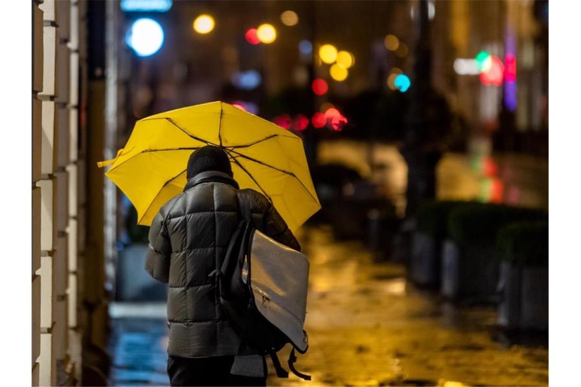 Ein Passant geht bei Regen durch die Stadt. Foto: Peter Kneffel/dpa/Symbolbild