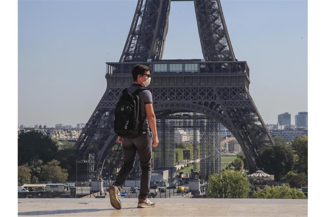 Ein Passant geht mit Mundschutzmaske über den Place du Trocadéro, während im Hintergrund ein Teil des Eiffelturms zu sehen ist. Foto: Michel Euler/AP/dpa