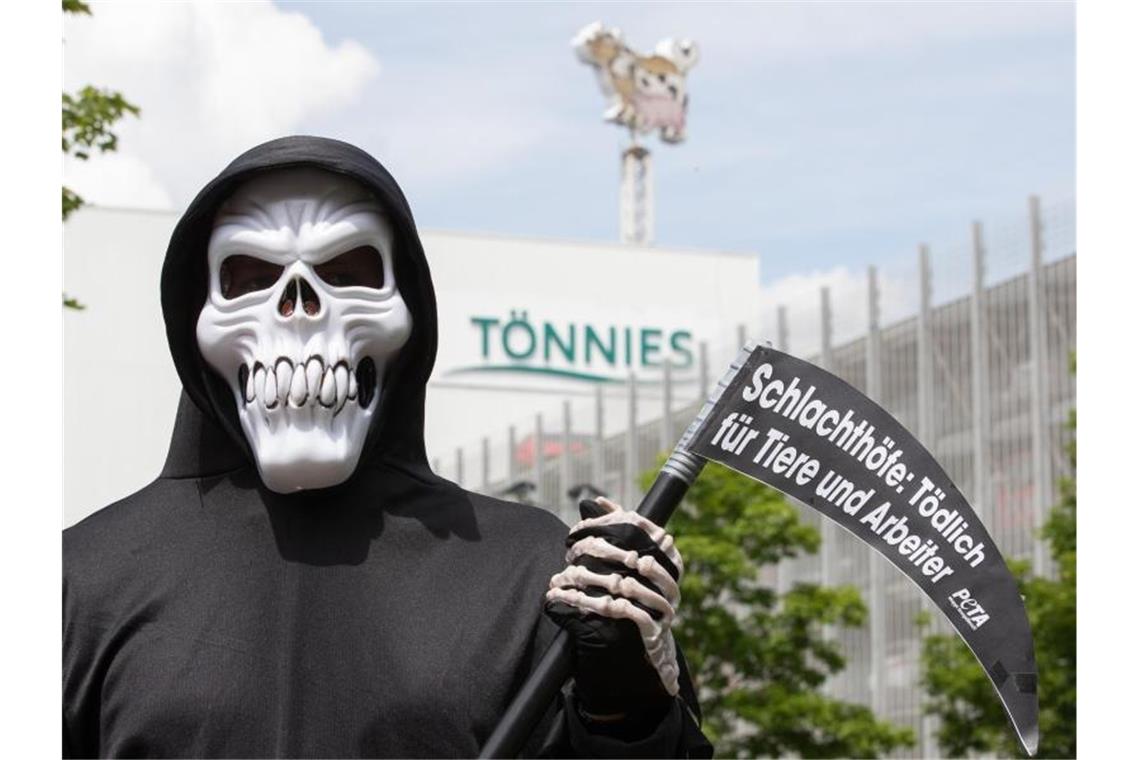 Ein Peta-Aktivist, verkleidet als Tod, protestiert vor dem Tönnies-Werk in Rheda-Wiedenbrück. Foto: Friso Gentsch/dpa