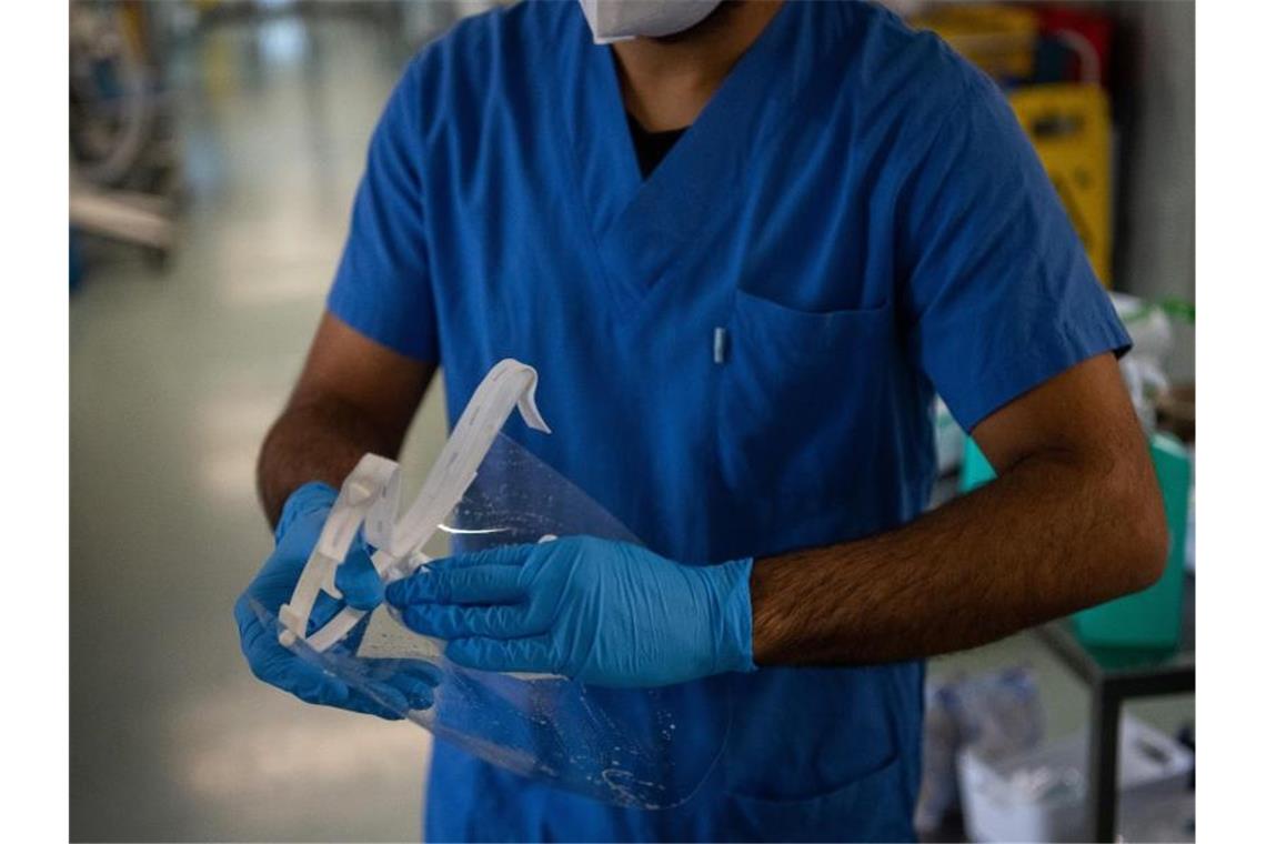 Kliniken: Keine höheren Kündigungszahlen wegen Impfpflicht Ein Pfleger desinfiziert auf einer Covid-Intensivstation sein Visier. Foto: Sebastian Gollnow/dpa