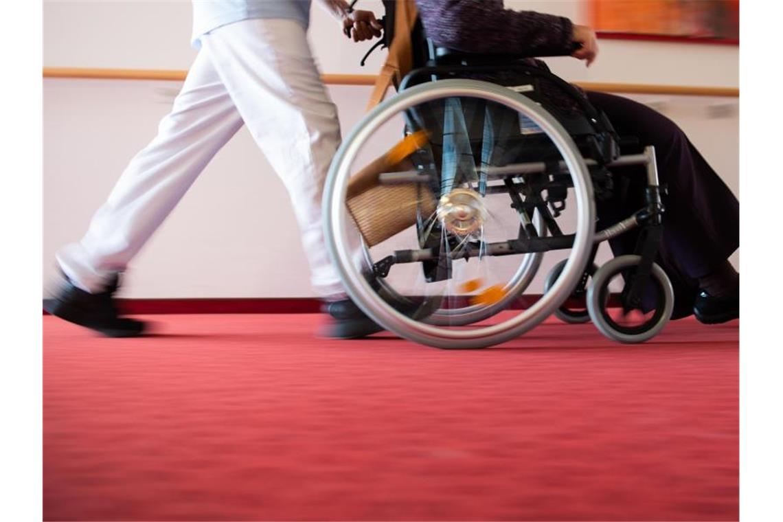 Ein Pfleger eines Pflegeheims schiebt eine Bewohnerin mit einem Rollstuhl. Foto: Tom Weller/dpa/Symbolbild