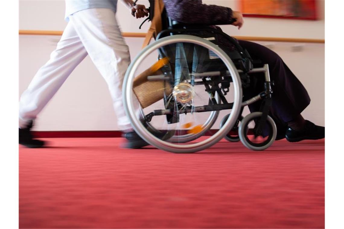 Ein Pfleger schiebt eine Bewohnerin mit einem Rollstuhl. Foto: Tom Weller/dpa/Symbolbild