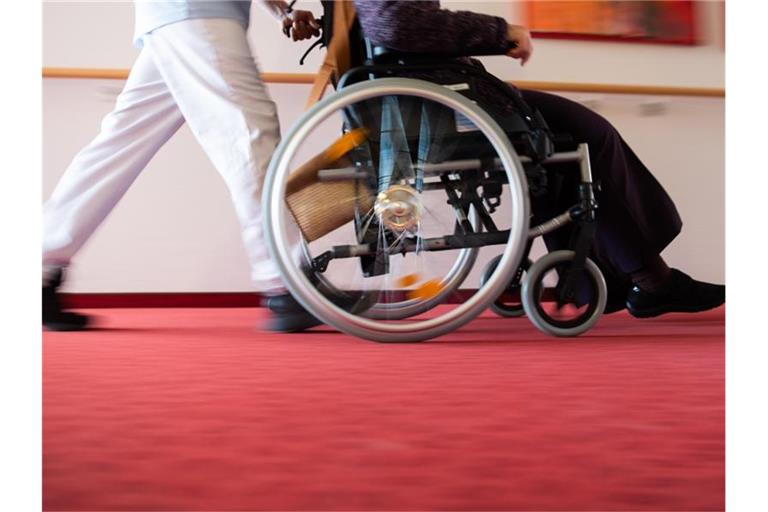 Ein Pfleger schiebt eine Frau in einem Rollstuhl. Foto: Tom Weller/dpa/Archivbild