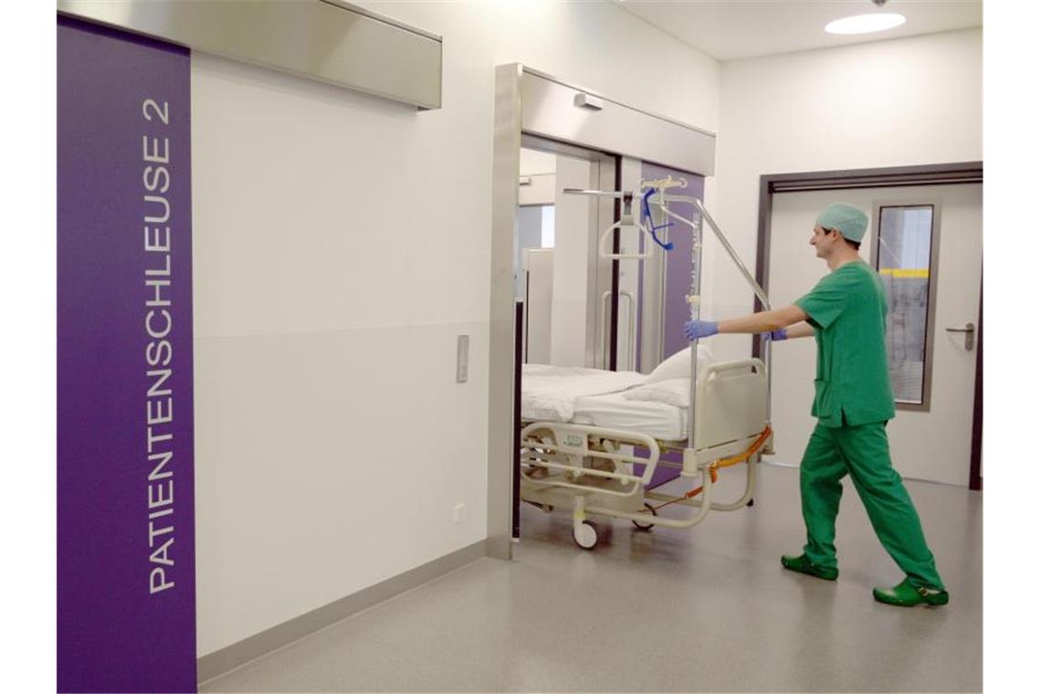 Personalmangel: Krankenhäuser schließen Abteilungen Ein Pfleger schiebt in einem Krankenhaus in Baden-Württemberg ein Bett in den Operationstrakt. Foto: Patrick Seeger/dpa/Archivbild