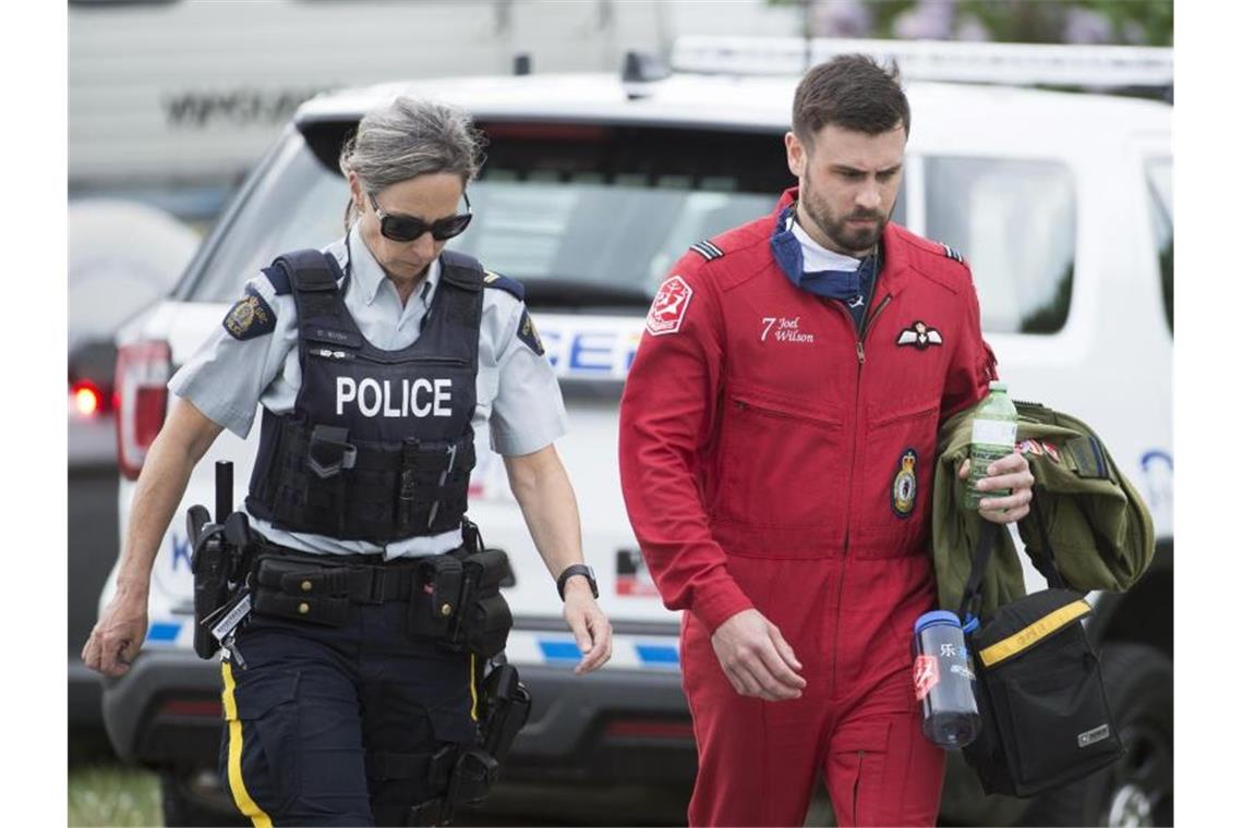 Ein Pilot geht mit einer Polizistin an der Absturzstelle vorbei. Foto: Jonathan Hayward/The Canadian Press/AP/dpa