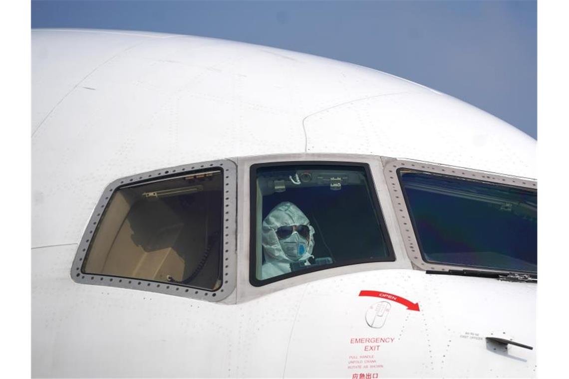 Ein Pilot mit Schutzanzug im Cockpit auf dem Internationalen Flughafen Wuhan-Tianhe. Foto: Cheng Min/XinHua/dpa
