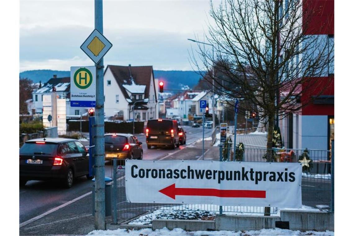 Ein Plakat mit dem Hinweis auf eine „Coronaschwerpunktpraxis“ hängt an einem Zaun. Foto: Philipp von Ditfurth/dpa