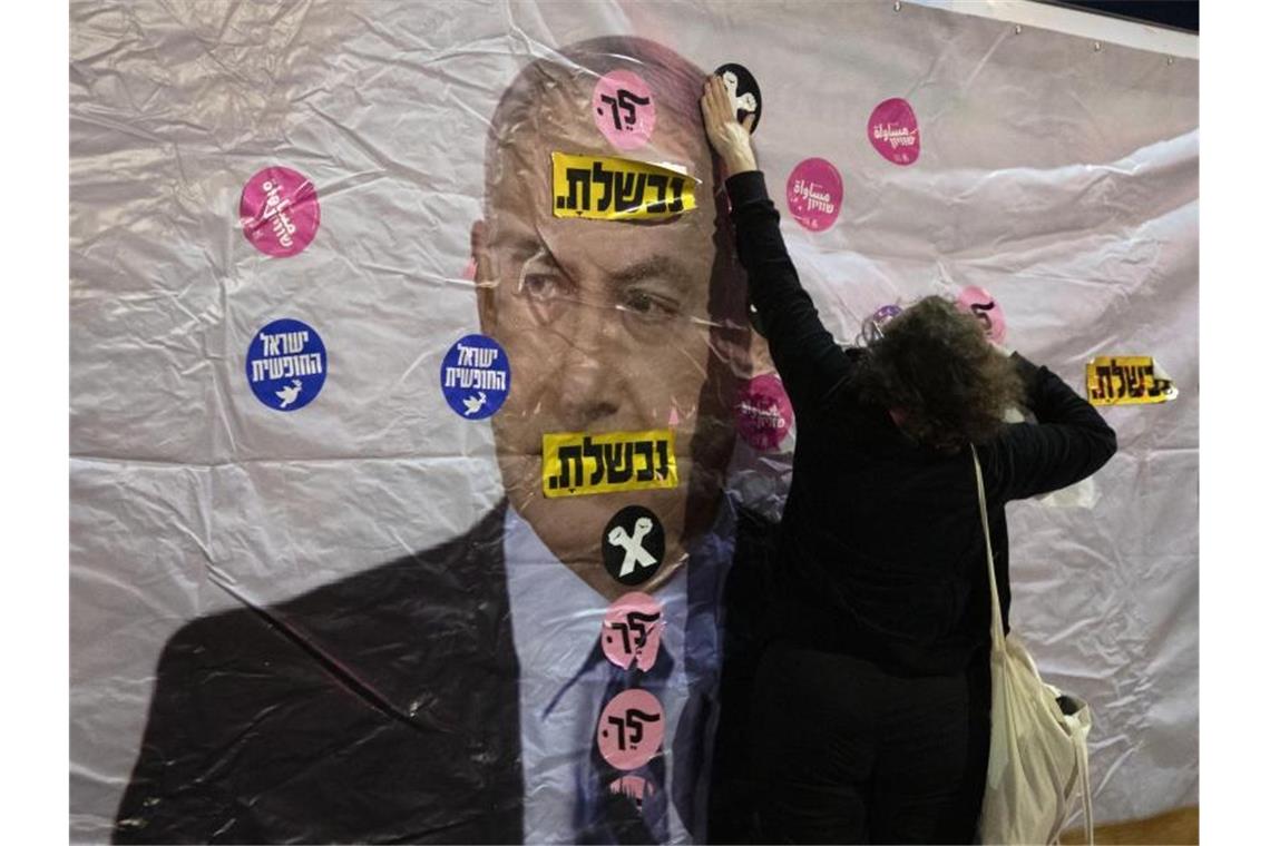 Ein Plakat mit dem Konterfei von Israels Premierminister Netanjahu wird mit Aufklebern überklebt. Foto: Sebastian Scheiner/AP/dpa