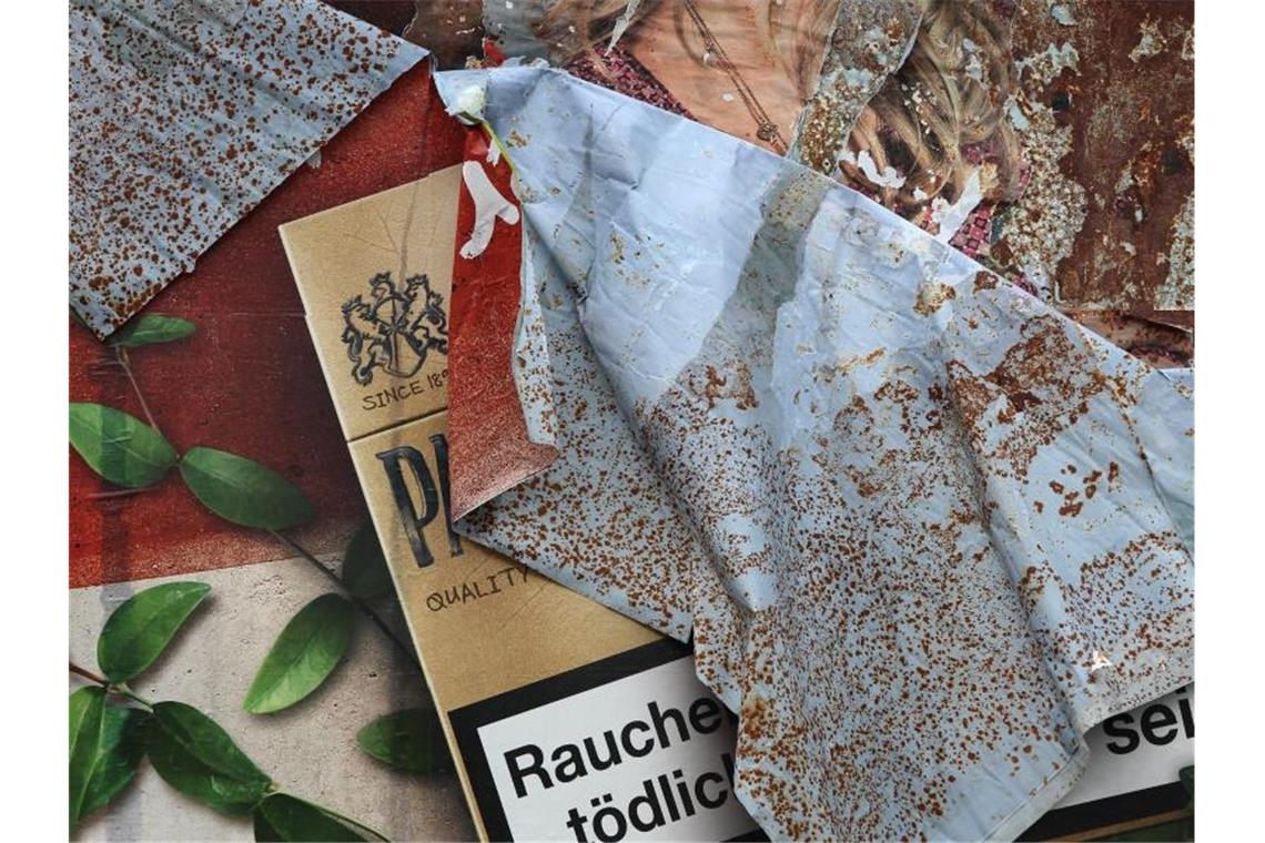 Ein Plakat mit Zigarettenwerbung löst sich von einer Plakatwand. Foto: picture alliance / dpa