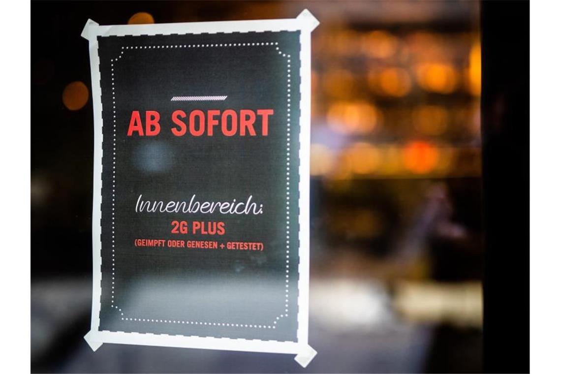 Ein Plakat weist Gäste am Eingang eines Restaurants in Stuttgart auf die neue 2G Plus Regel hin. Foto: Christoph Schmidt/dpa