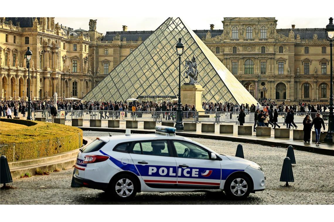 Ein Polizeiauto parkt im Hof des Louvre während Besucher vor der Glaspyramide in einer Schlange stehen. (Symbolbild)