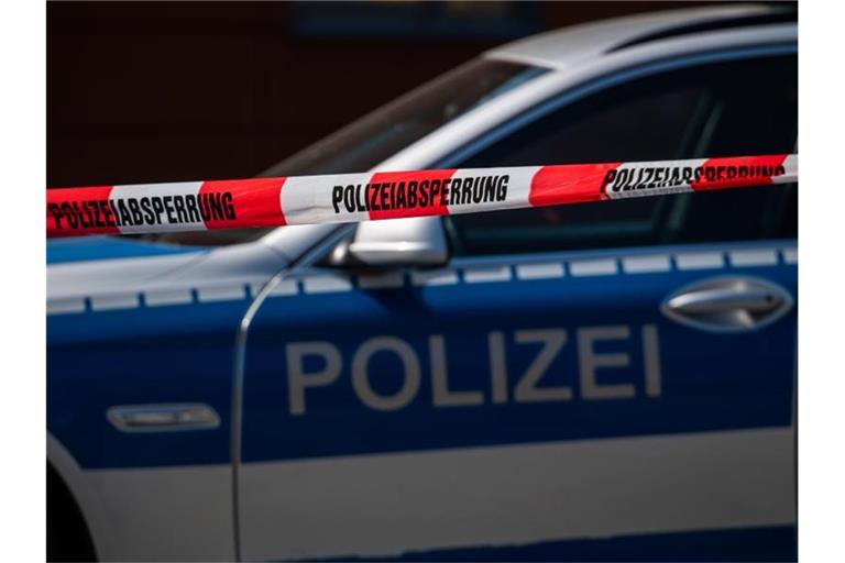 Ein Polizeiauto steht hinter einem Absperrband der Polizei. Foto: Robert Michael/dpa-Zentralbild/dpa/Archivbild