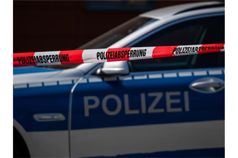Ein Polizeiauto steht hinter einem Absperrband der Polizei. Foto: Robert Michael/dpa-Zentralbild/dpa/Archivbild