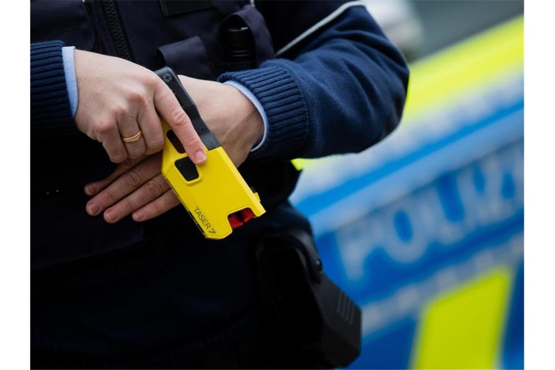 Ein Polizeibeamter hält ein sogenanntes Distanz-Elektro-Impulsgerät in der Hand. Foto: Rolf Vennenbernd/dpa/Symbolbild