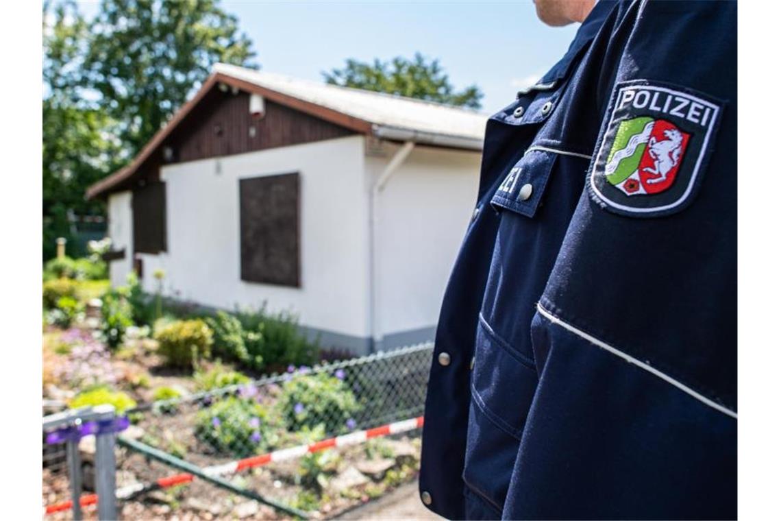 Ein Polizeibeamter steht vor der Gartenlaube in Münster, wo der vermutliche Haupttäter Teile seiner Server-Anlage unterbrachte. Foto: Guido Kirchner/dpa