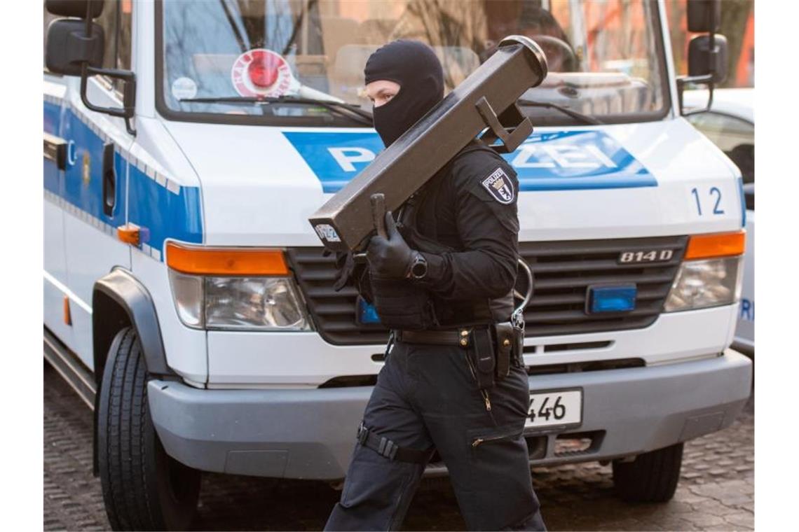 Ein Polizeibeamter trägt nach einer Razzia im Märkischen Viertel in Berlin eine Ramme. Foto: Christophe Gateau/dpa