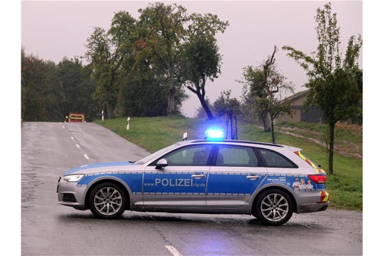 Ein Polizeifahrzeug blockiert eine Straße mit eingeschaltetem Blaulicht. F. Foto: Harald Tittel/dpa