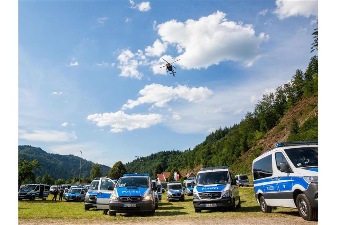 Bewaffneter Mann weiterhin auf Flucht Ein Polizeihubschrauber fliegt über einen Sportplatz, auf dem Polizeifahrzeuge stehen. Foto: Philipp von Ditfurth/dpa