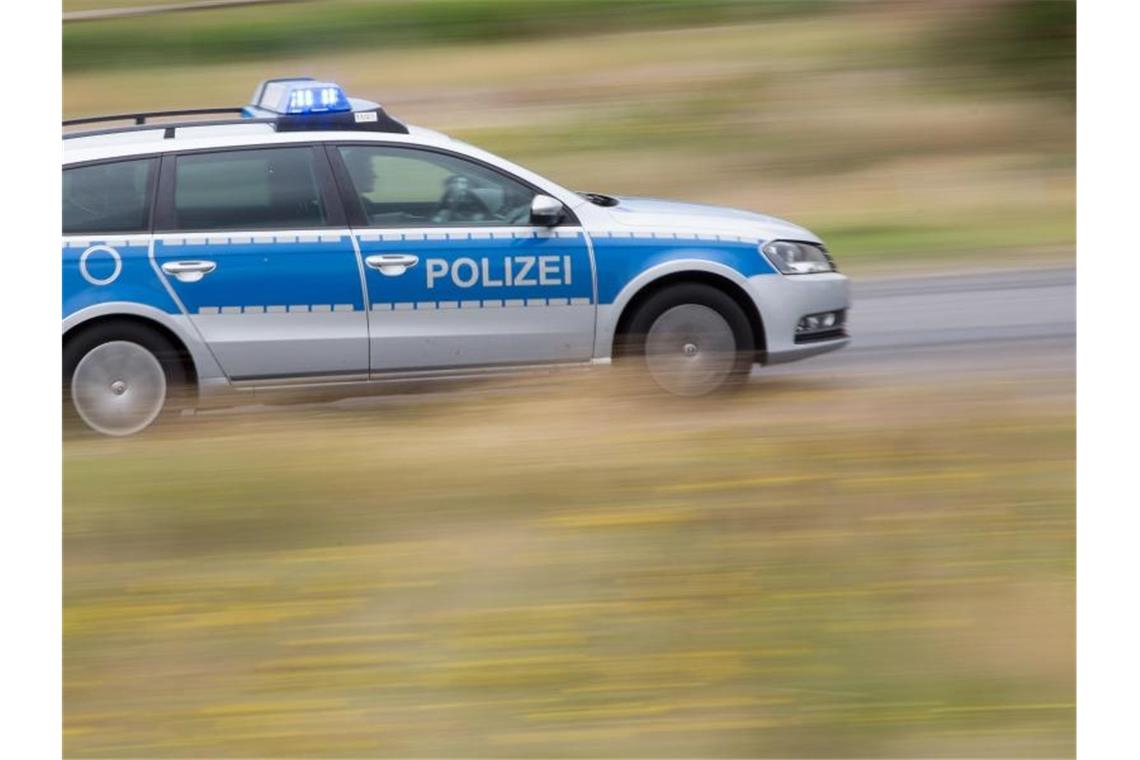 Ein Polizeiwagen mit Blaulicht fährt über eine Straße. Foto: Friso Gentsch/dpa/Archivbild