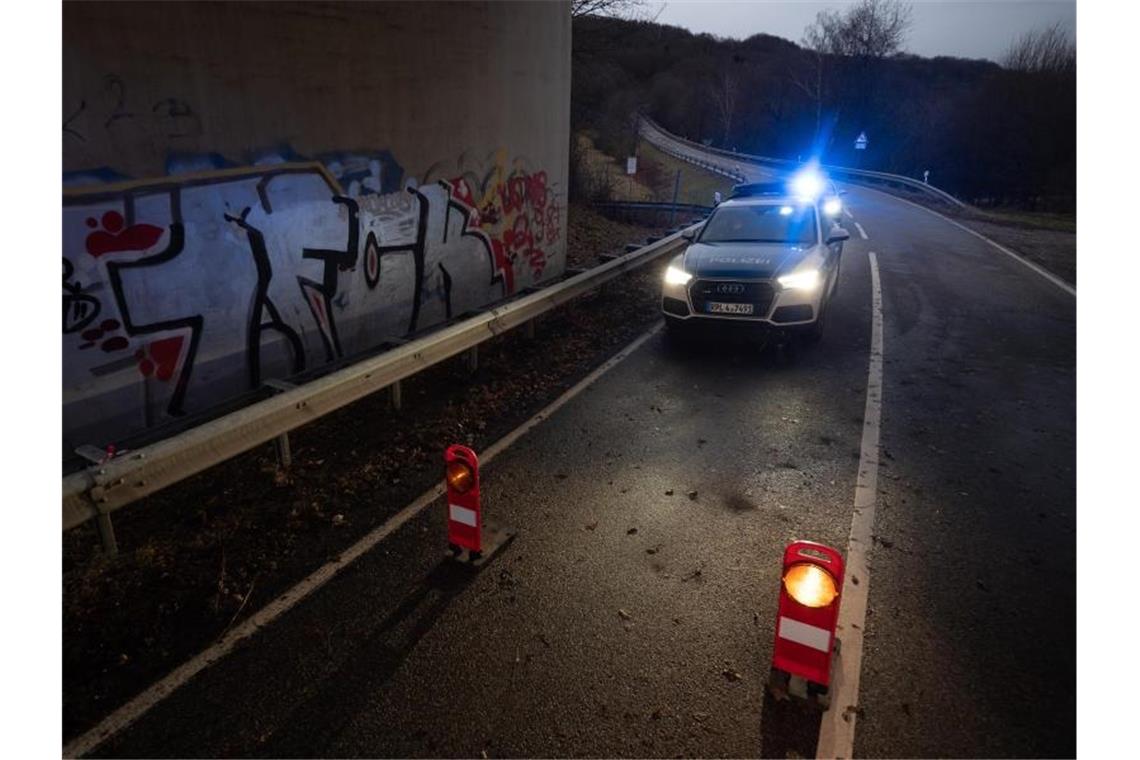 Polizisten erschossen - Zwei Verdächtige festgenommen Ein Polizeiwagen steht an einer Absperrung an der Kreisstraße 22 rund einen Kilometer von dem Tatort entfernt. Foto: Sebastian Gollnow/dpa
