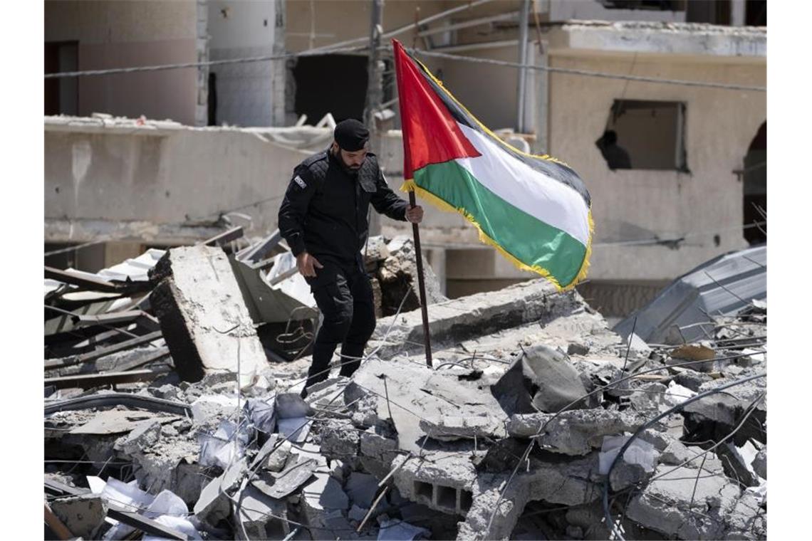 Waffenruhe in Nahost hält - Biden für Zwei-Staaten-Lösung Ein Polizist der Hamas entfernt eine palästinensische Fahne von einem Trümmerhaufen eines Bahnhofsgebäudes, das bei Luftangriffen zerstört worden war. Foto: John Minchillo/AP/dpa